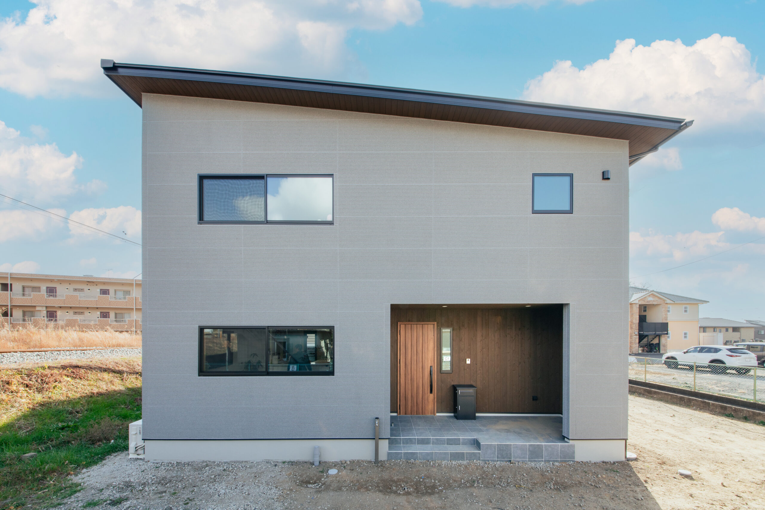 やわらかなグレーの外壁に、木目のアクセントが映えるモダンな佇まい
