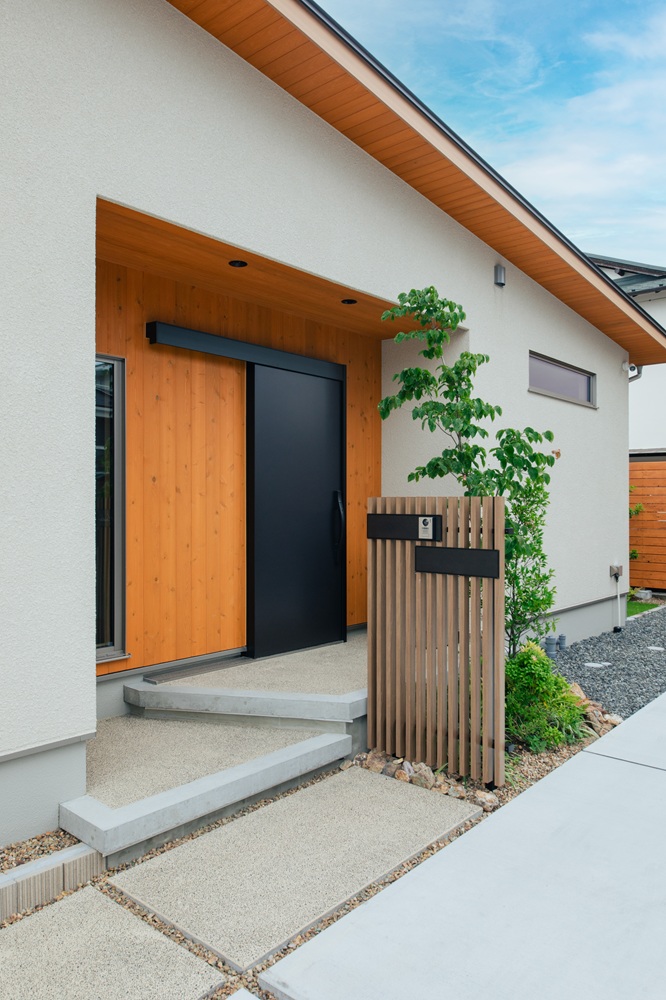 アイボリーの塗り壁風と玄関廻りを杉板張りで仕上げたシンプルで上質な住まい